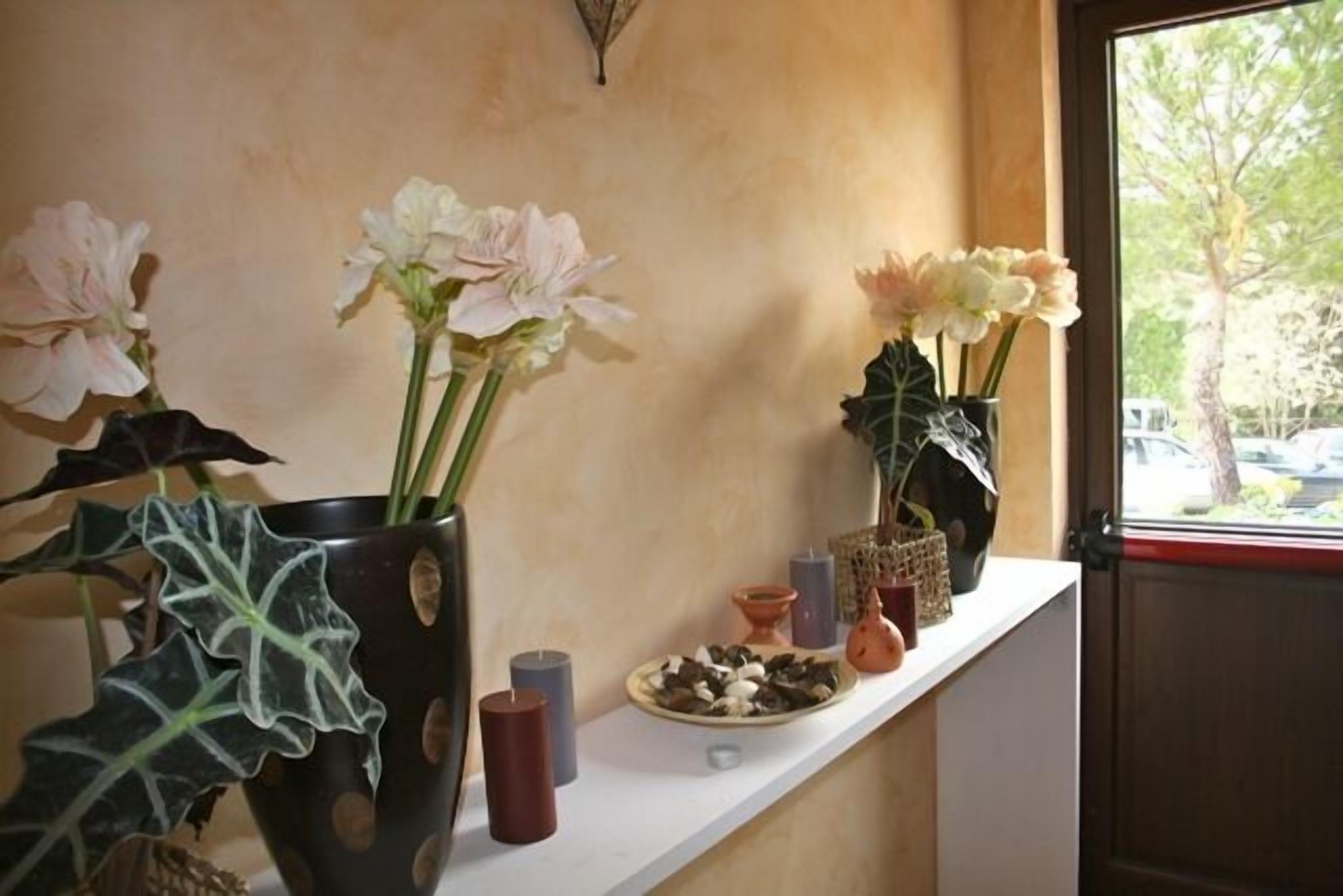 A shelf with potted plants, candles, and decorative items.