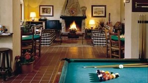 Una habitación acogedora con mesa de billar, chimenea y asientos cómodos.