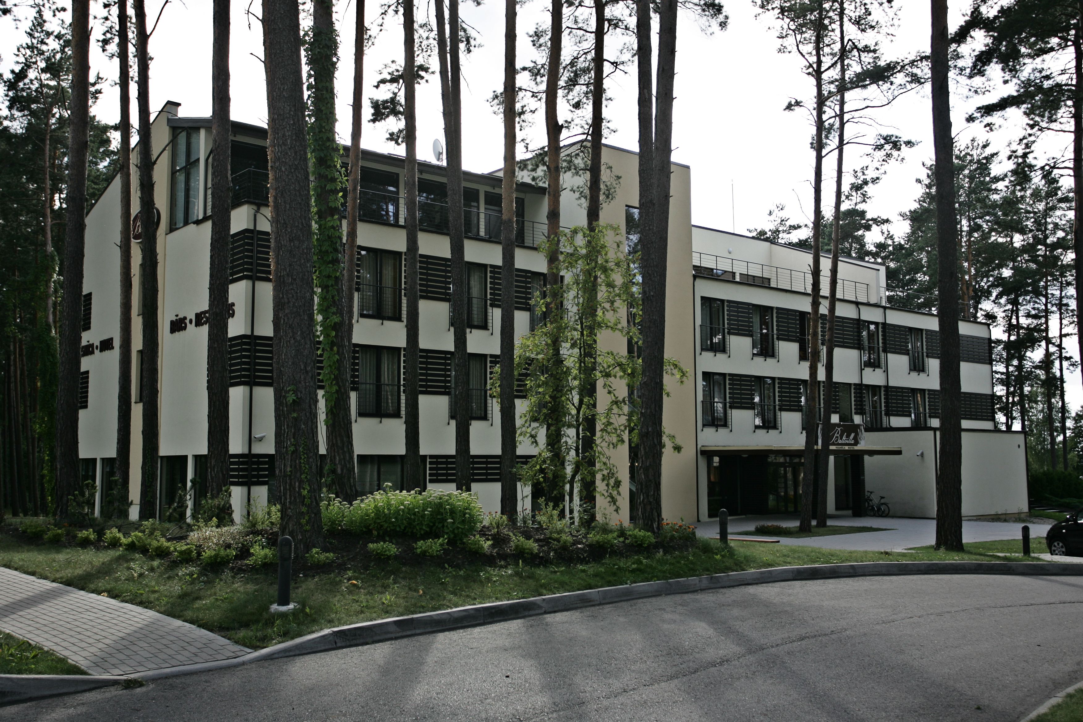 A modern building with a flat roof, large windows, and a parking area.
