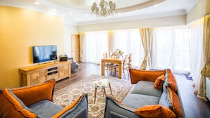 A spacious living room with a television, sofa, and dining table. - Hotel Baltvilla (Garkalnes novads)