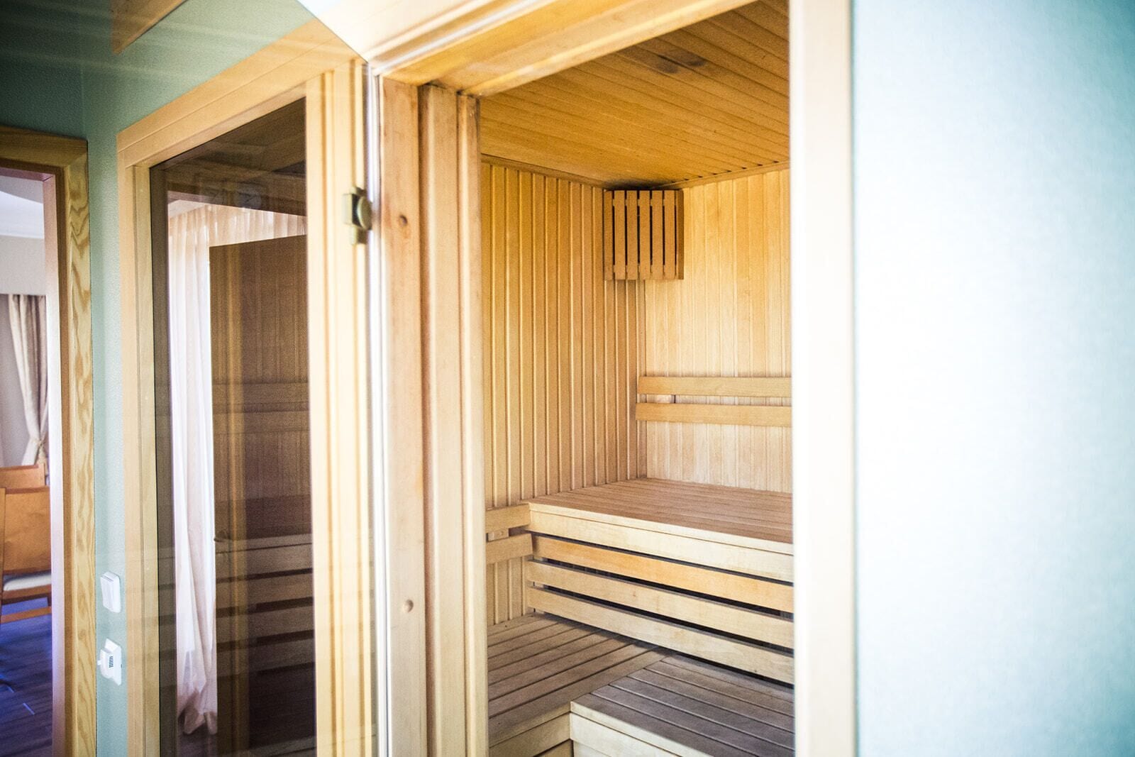 A sauna with wooden benches and a glass door.