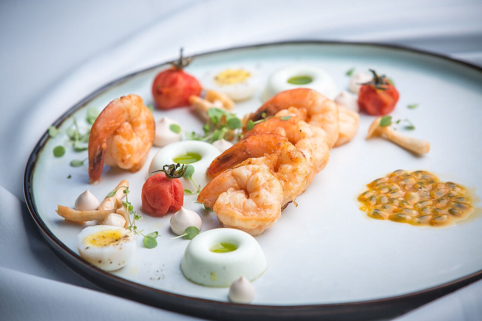 A plate of food with shrimp, tomatoes, and other garnishes.