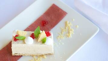 Une part de gâteau au fromage, garnie de fruits rouges et d’une feuille de menthe, présentée sur une assiette blanche.