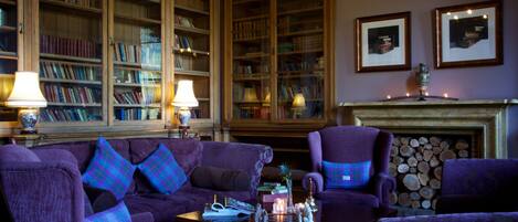A library with bookshelves, a fireplace, and purple furniture.