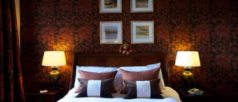 Una habitación de hotel con una cama grande, dos lámparas de noche y cuatro cuadros enmarcados en la pared.