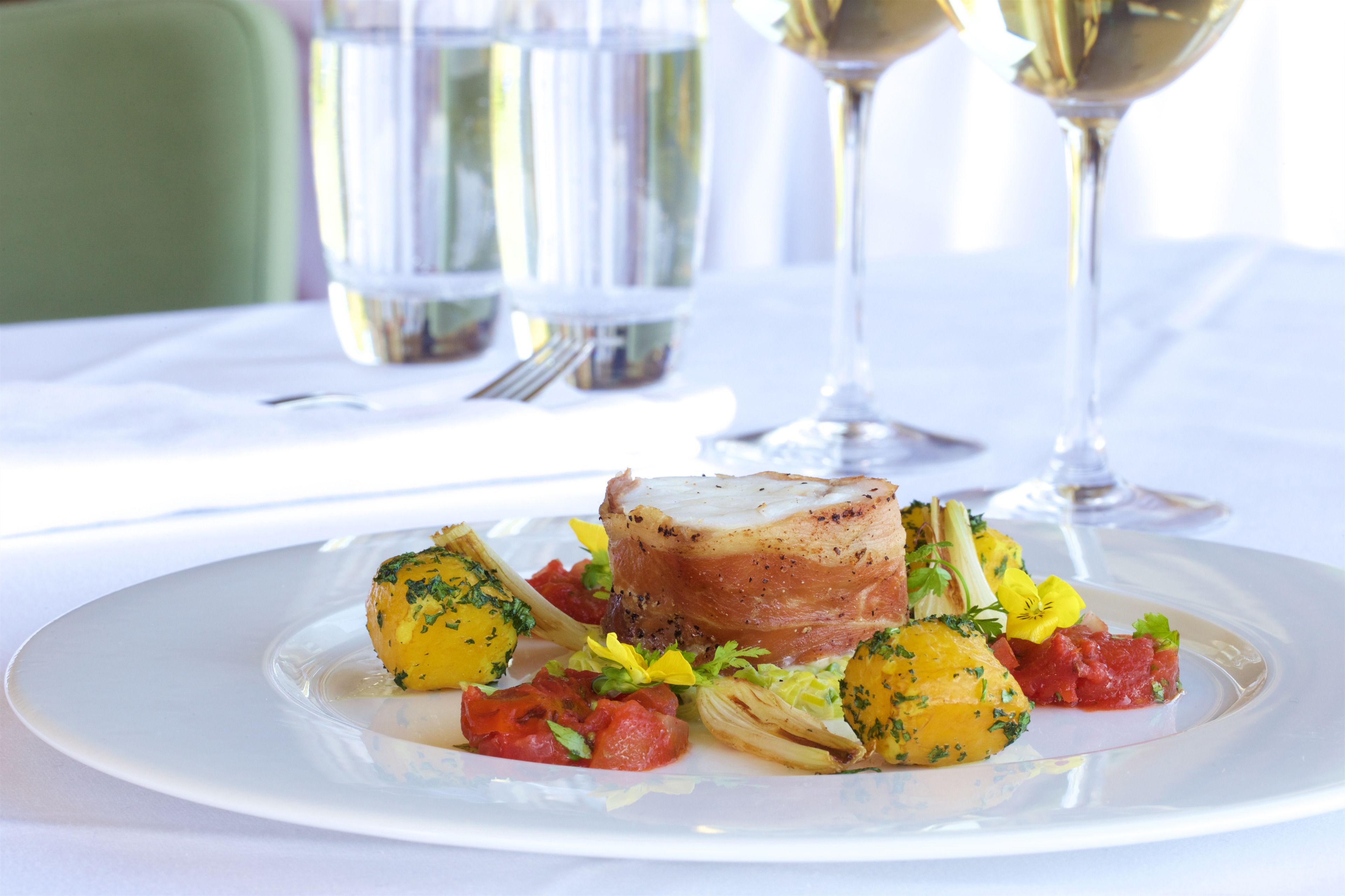 A plate of food with a piece of meat, vegetables, and a flower garnish.