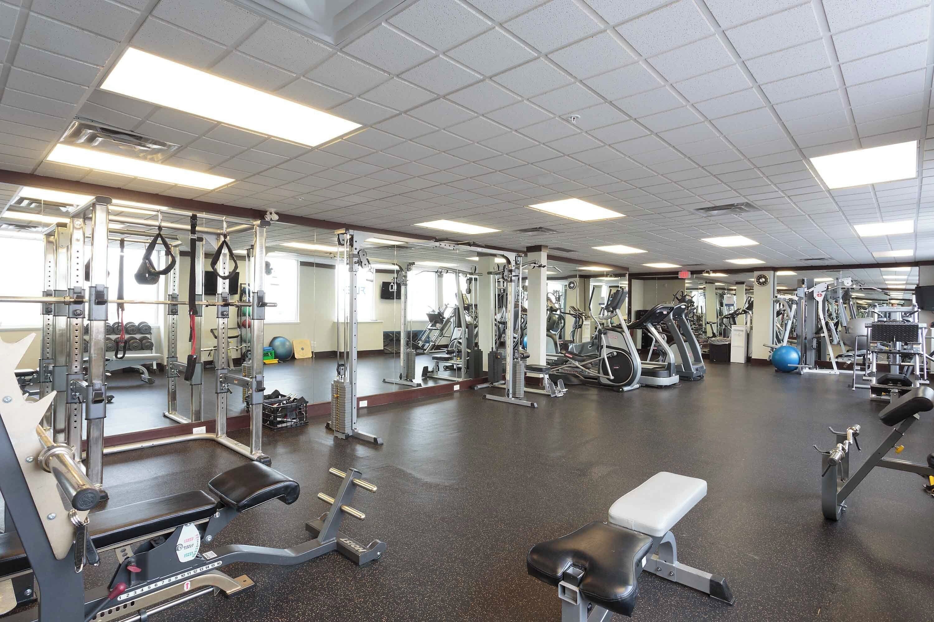 A gym with various exercise equipment, a mirrored wall, and a clean, spacious floor.