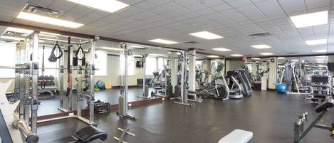 A gym with various exercise equipment, a mirrored wall, and a clean, spacious floor.