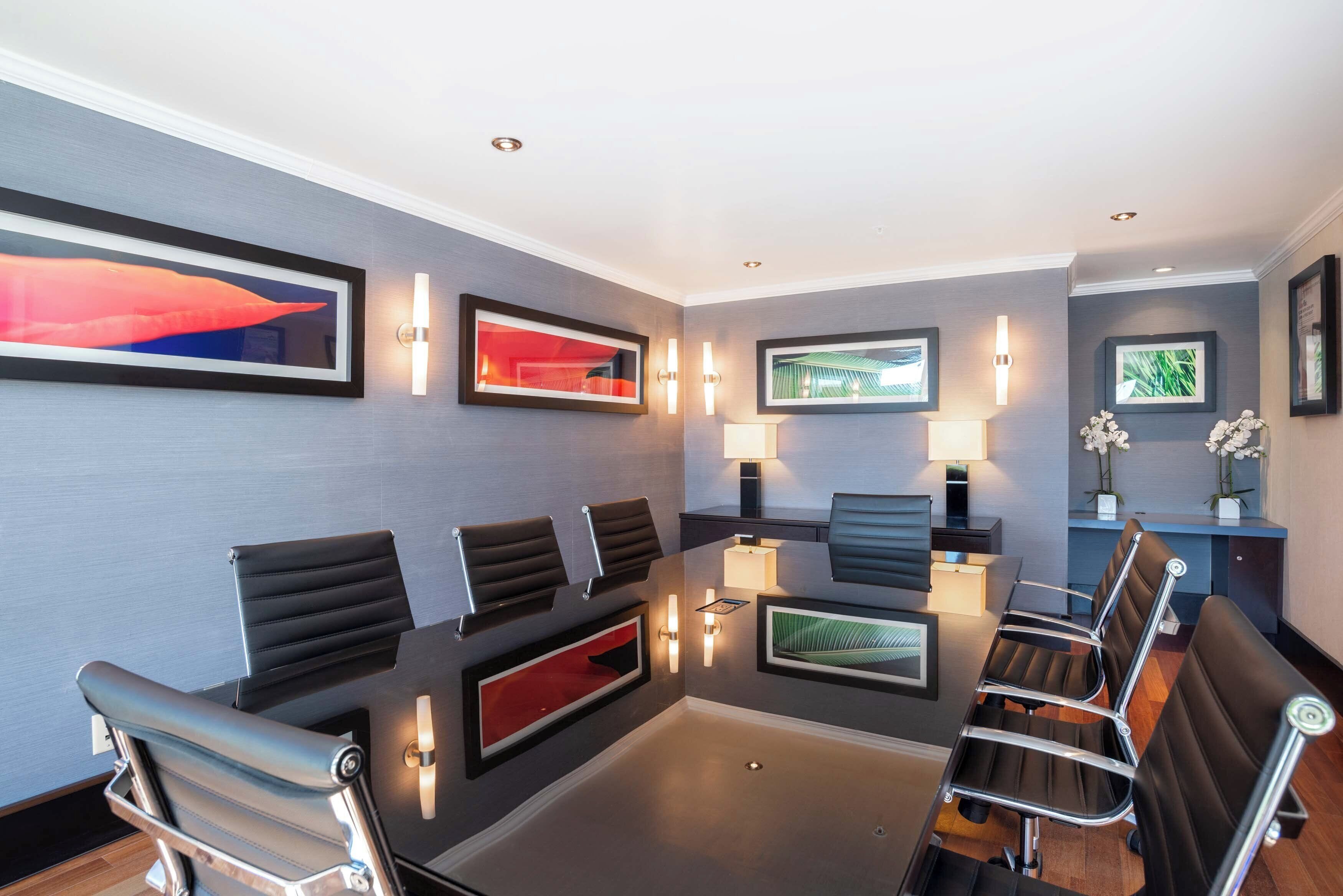 A hotel lobby with a reception desk, multiple seating areas, framed artwork, and wall-mounted lighting.