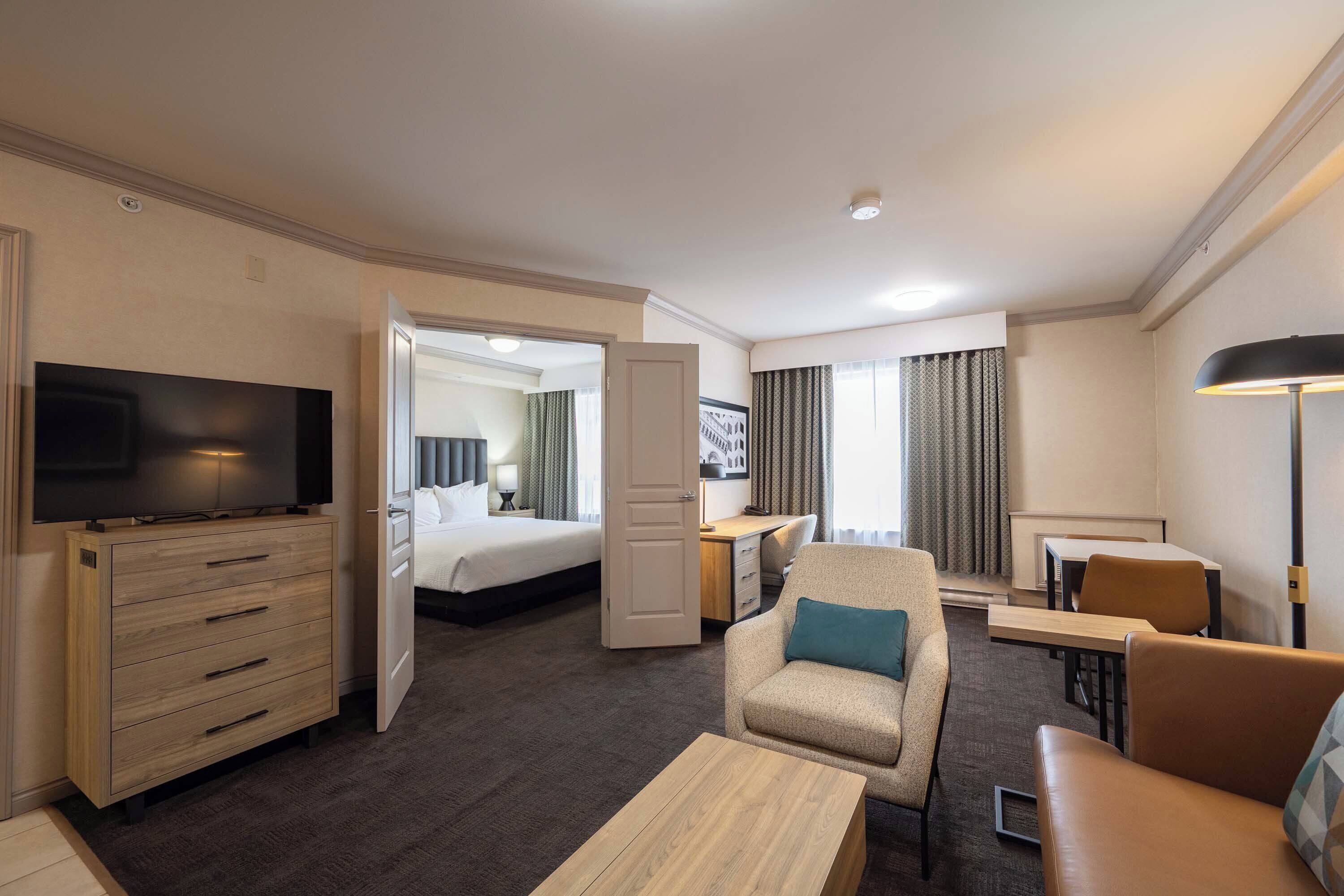 Una habitación de hotel con televisión, cama, escritorio, silla y sofá.