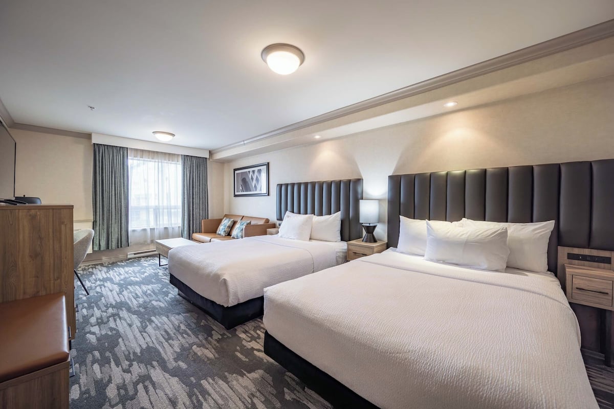 Une chambre d’hôtel avec deux lits, un bureau et une chaise.
