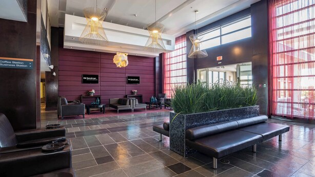 Eine moderne Lobby mit Sitzgelegenheiten, einer Kaffeestation und einem Arbeitsbereich.