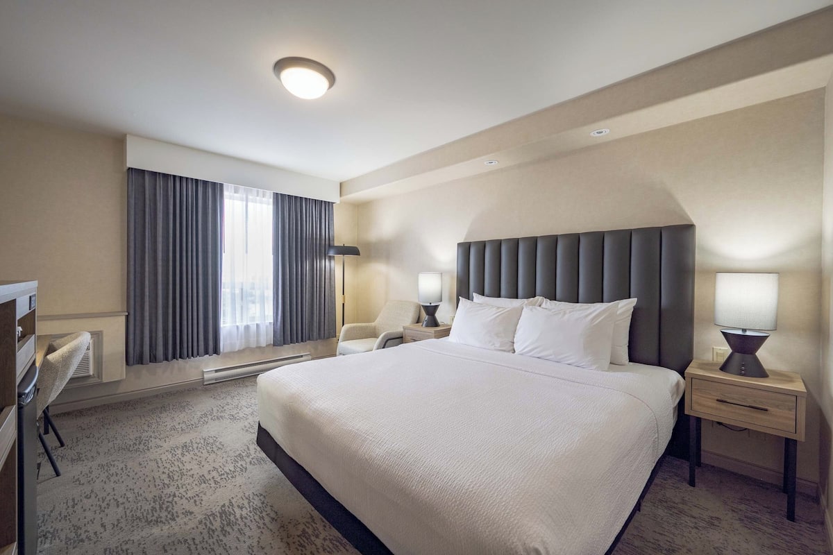 Une chambre d’hôtel avec un grand lit, des tables de chevet, un bureau et une chaise.