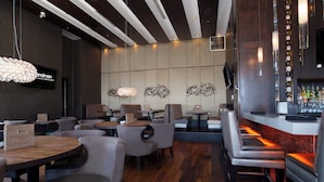 Ein modernes Restaurant mit Holztischen und -stühlen, einer Bar und dekorativer Wandgestaltung.