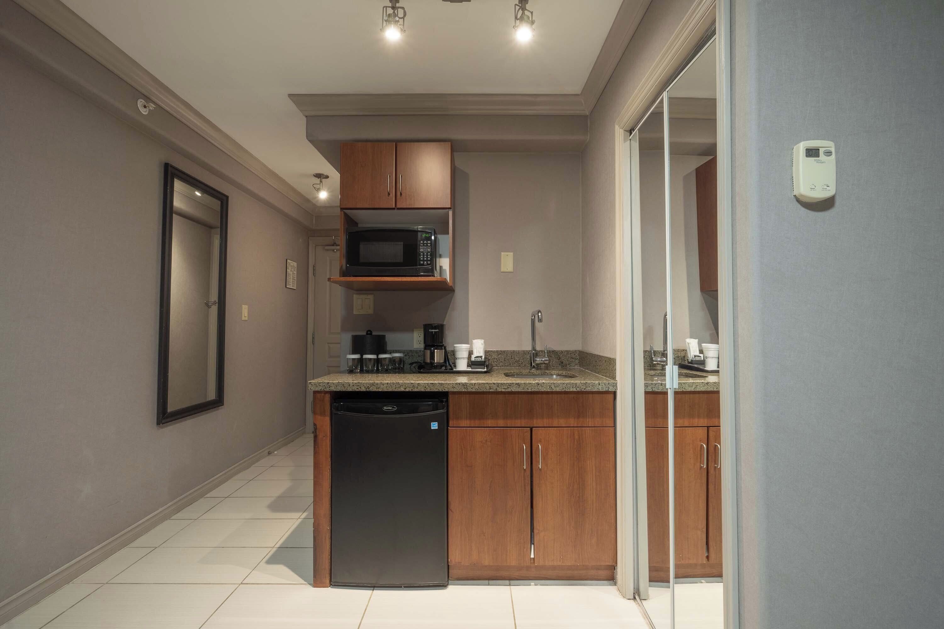 A compact kitchen with wooden cabinets, a built-in microwave, and a dishwasher.