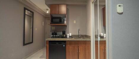 A compact kitchen with wooden cabinets, a built-in microwave, and a dishwasher.