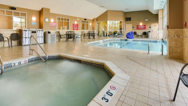An indoor swimming pool with a 30 ft depth sign, a reception area, and a 'No Lifeguard' warning sign.