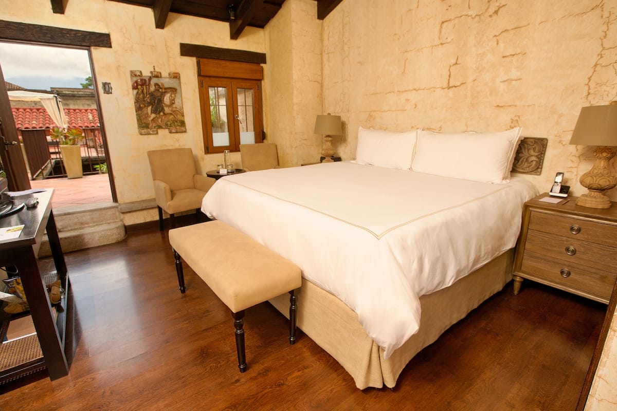 Un dormitorio con una cama grande, un banco, un escritorio y una silla.