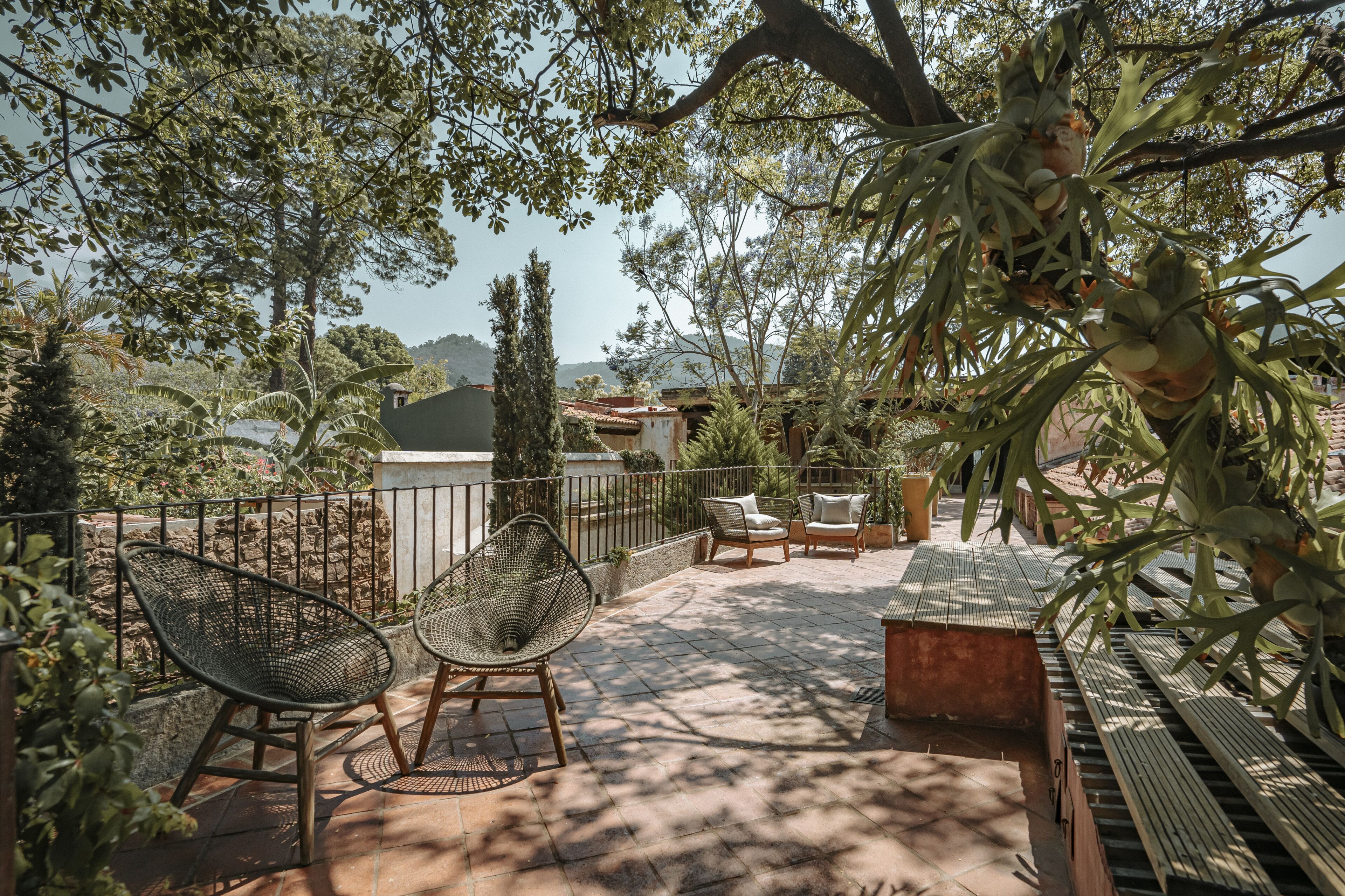 An outdoor patio with wicker chairs, a wooden bench, and a small table.