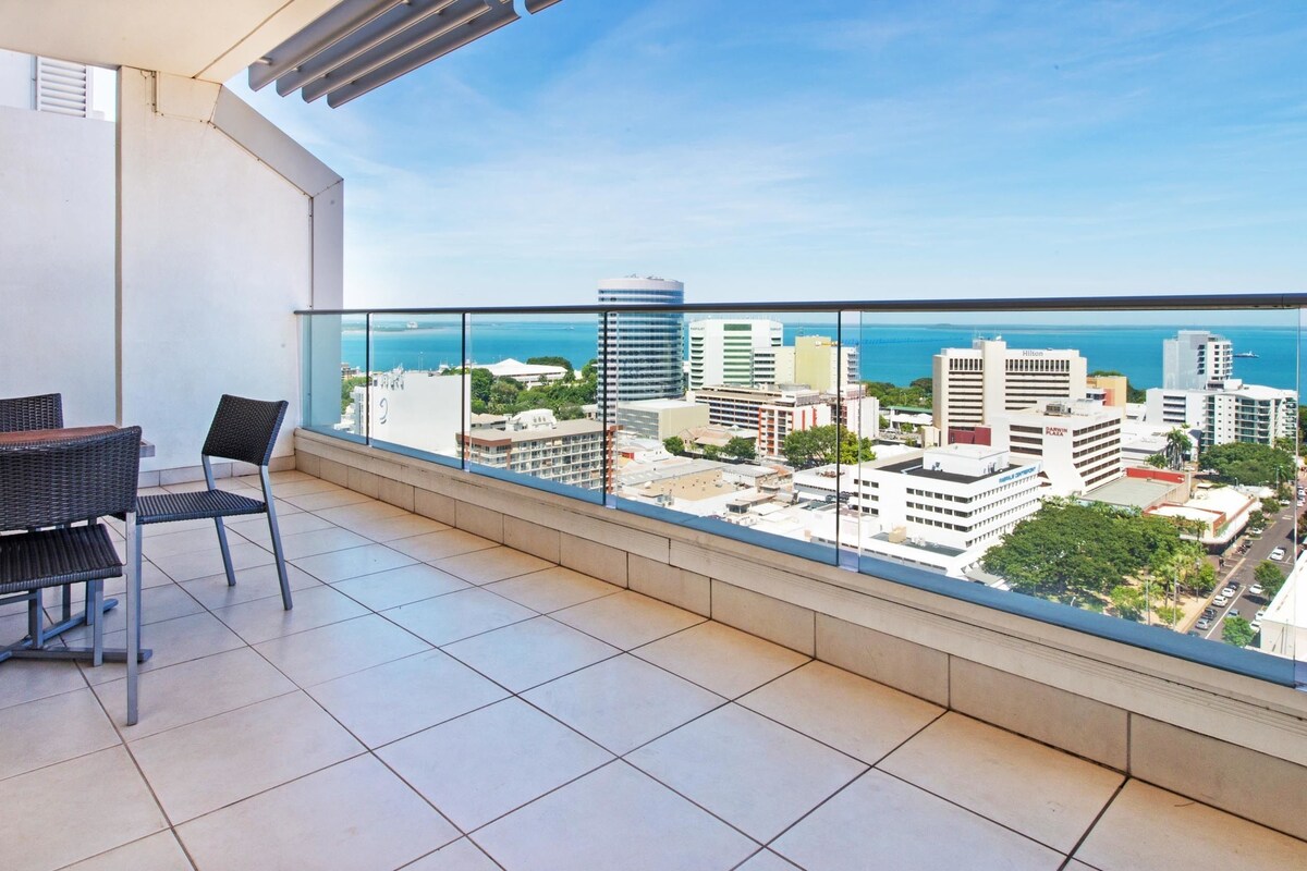 A balcony with a view of a cityscape and the sea.