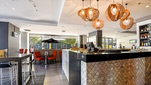 A modern hotel lobby with a bar area, seating, and a patterned wall. - Mantra Pandanas (Darwin)