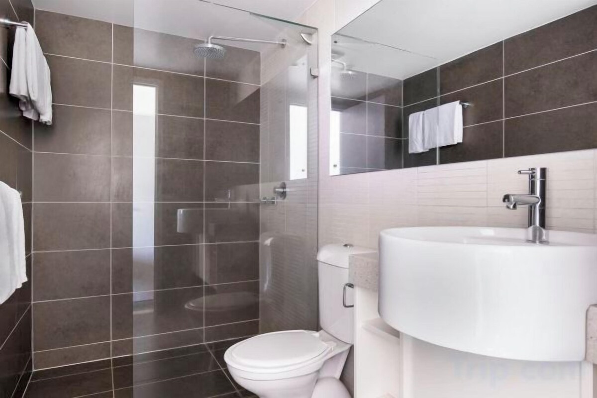 A modern bathroom with a glass-enclosed shower, a white toilet, and a large sink.