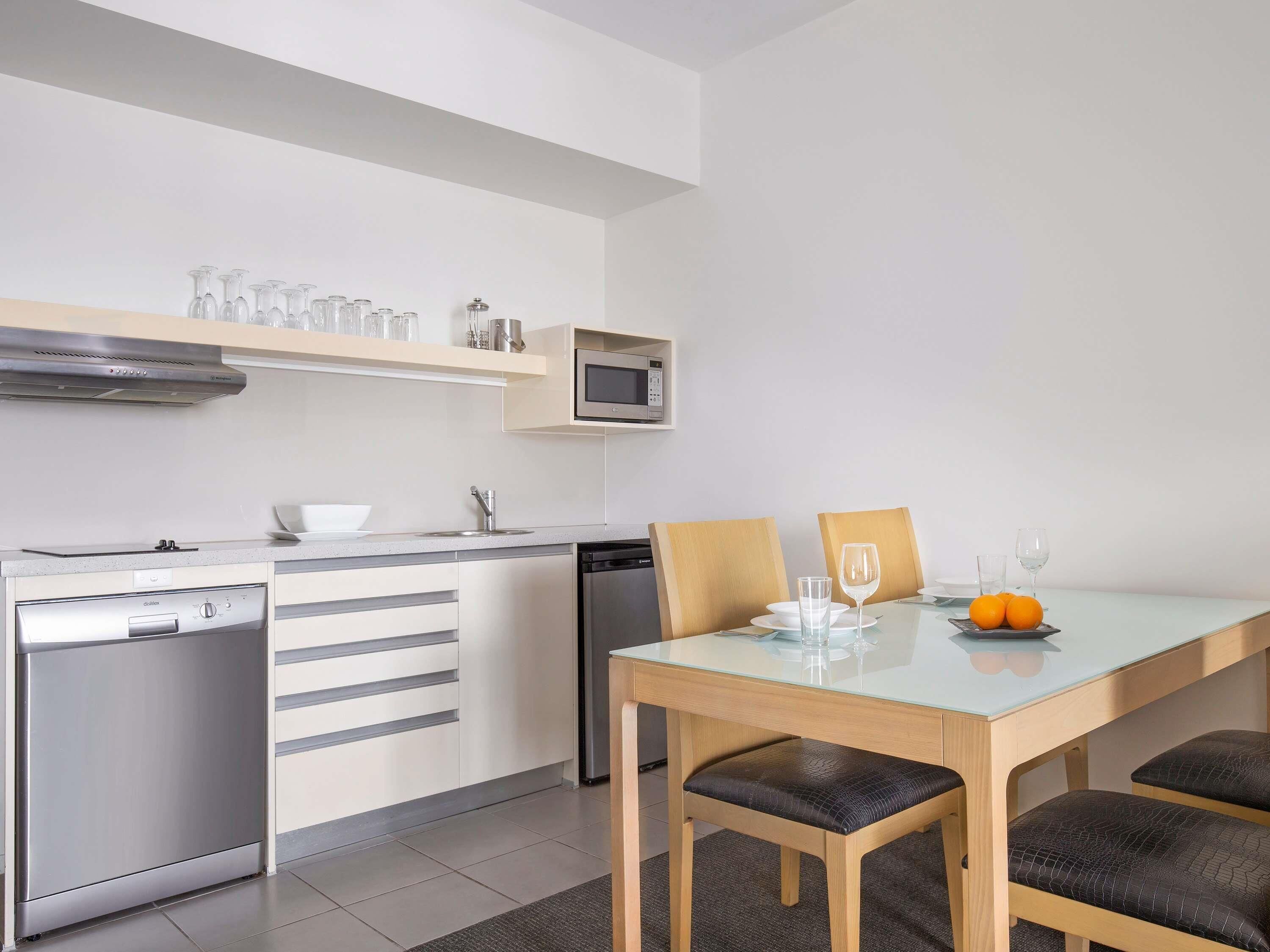Una cocina moderna equipada con lavavajillas, microondas y un comedor con mesa y sillas.