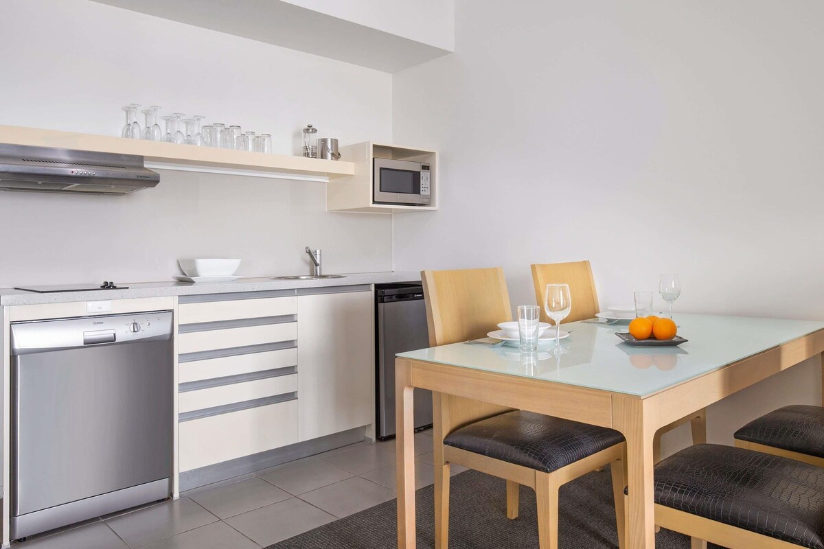 A modern kitchen with a dishwasher, microwave, and a dining area with a table and chairs.