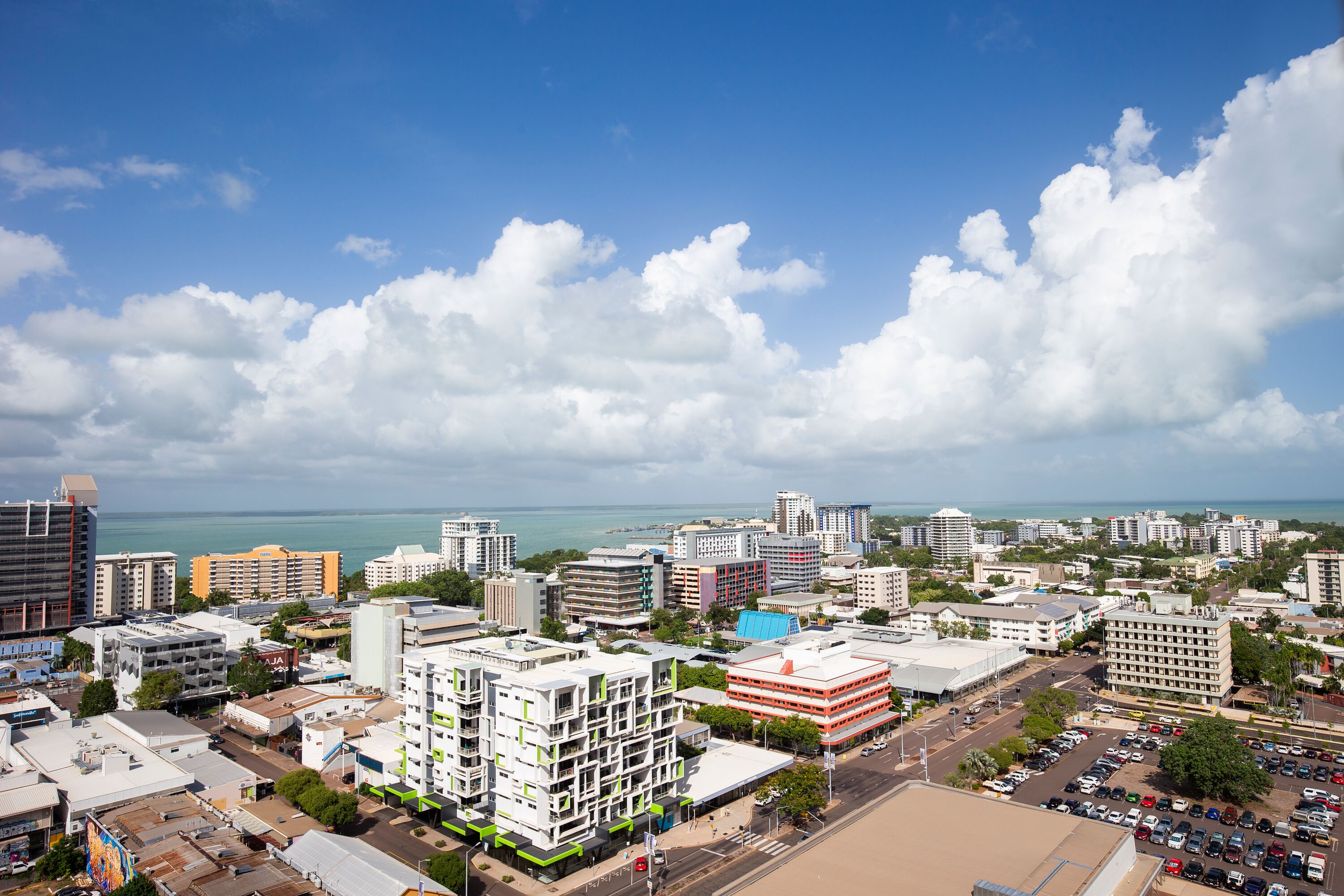 A coastal cityscape with modern buildings, a marina, and a clear view of the ocean.