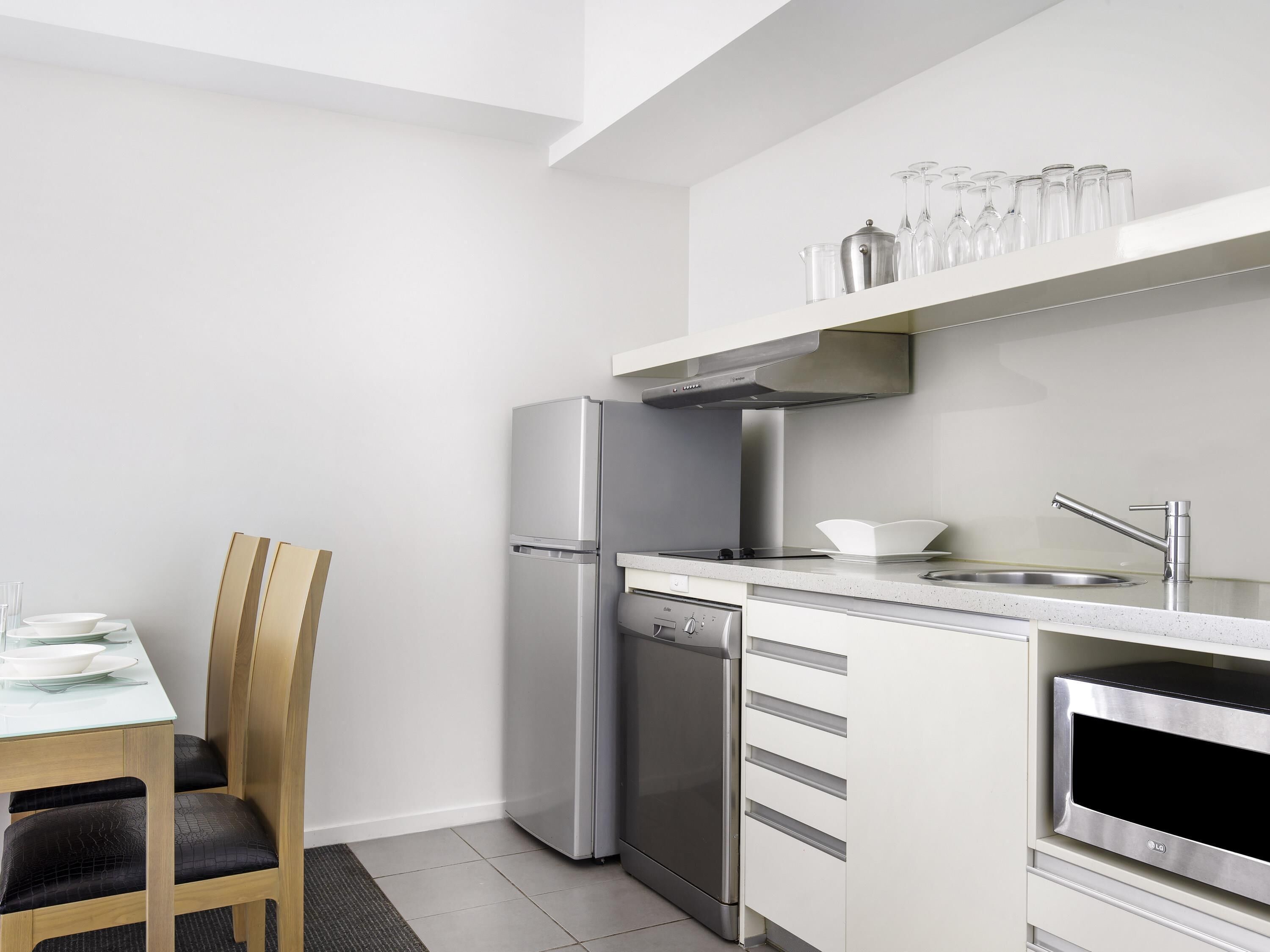 A modern kitchen with a built-in dishwasher, stainless steel appliances, and a dining area with a table and chairs.