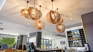 A modern bar area with hanging wicker light fixtures, a bar counter, and a wine rack filled with bottles. - Mantra Pandanas (Darwin)