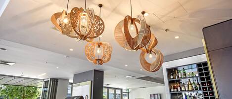 A modern bar area with hanging wicker light fixtures, a bar counter, and a wine rack filled with bottles.