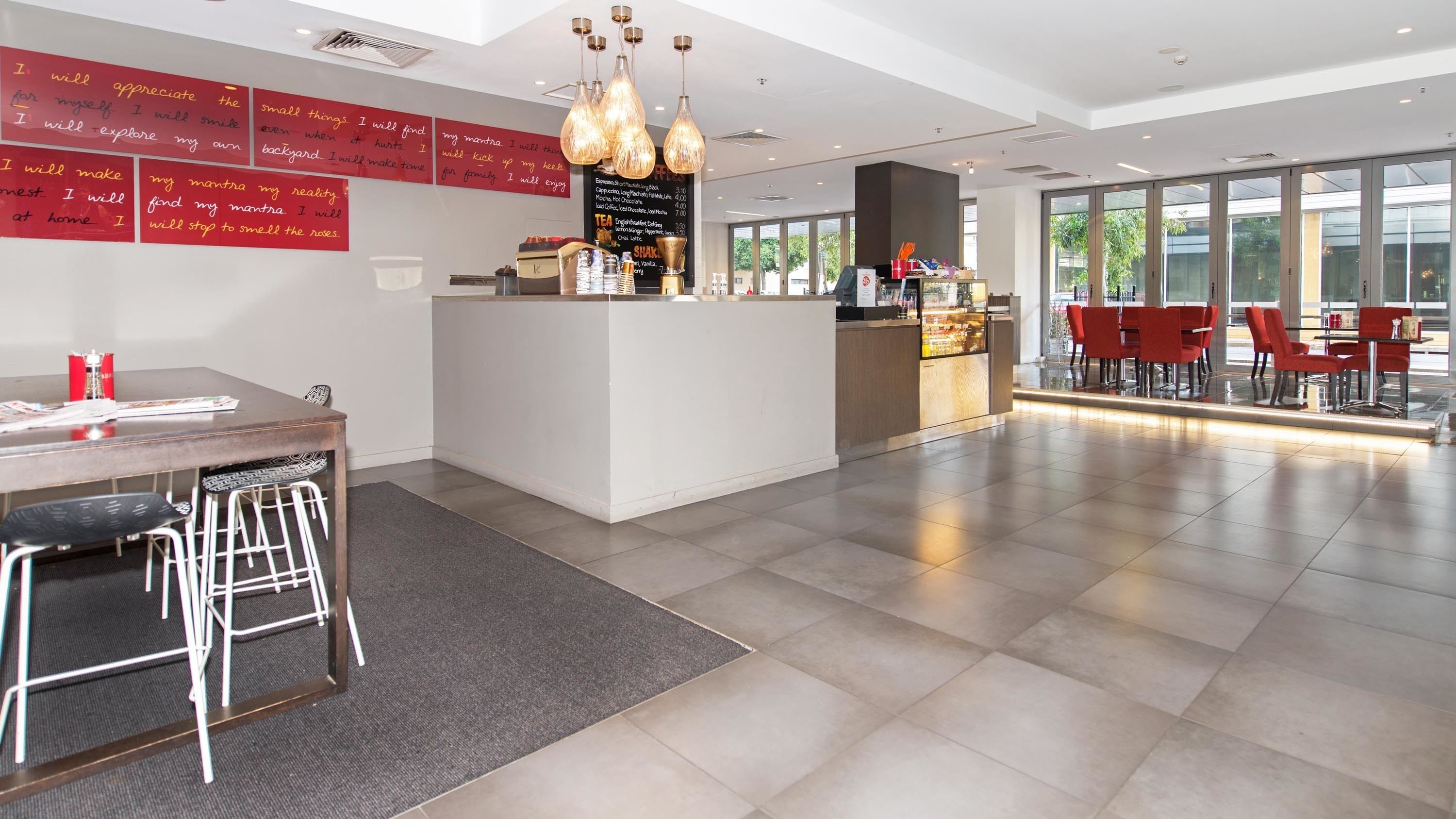 A modern cafe with a central counter, barista station, and seating area.