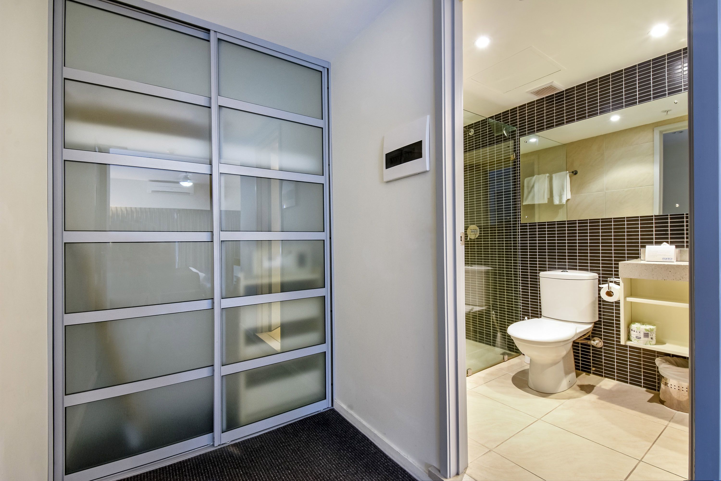 A bathroom with a toilet, a sink, and a mirror.