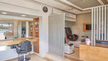 Un moderno salón de belleza con un espejo grande, una estación de lavado de cabello y una pantalla de televisión.