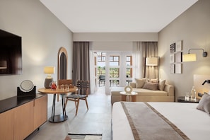 Een hotelkamer met een bed, een bureau met lamp, een stoel, een bank en uitzicht op buiten.