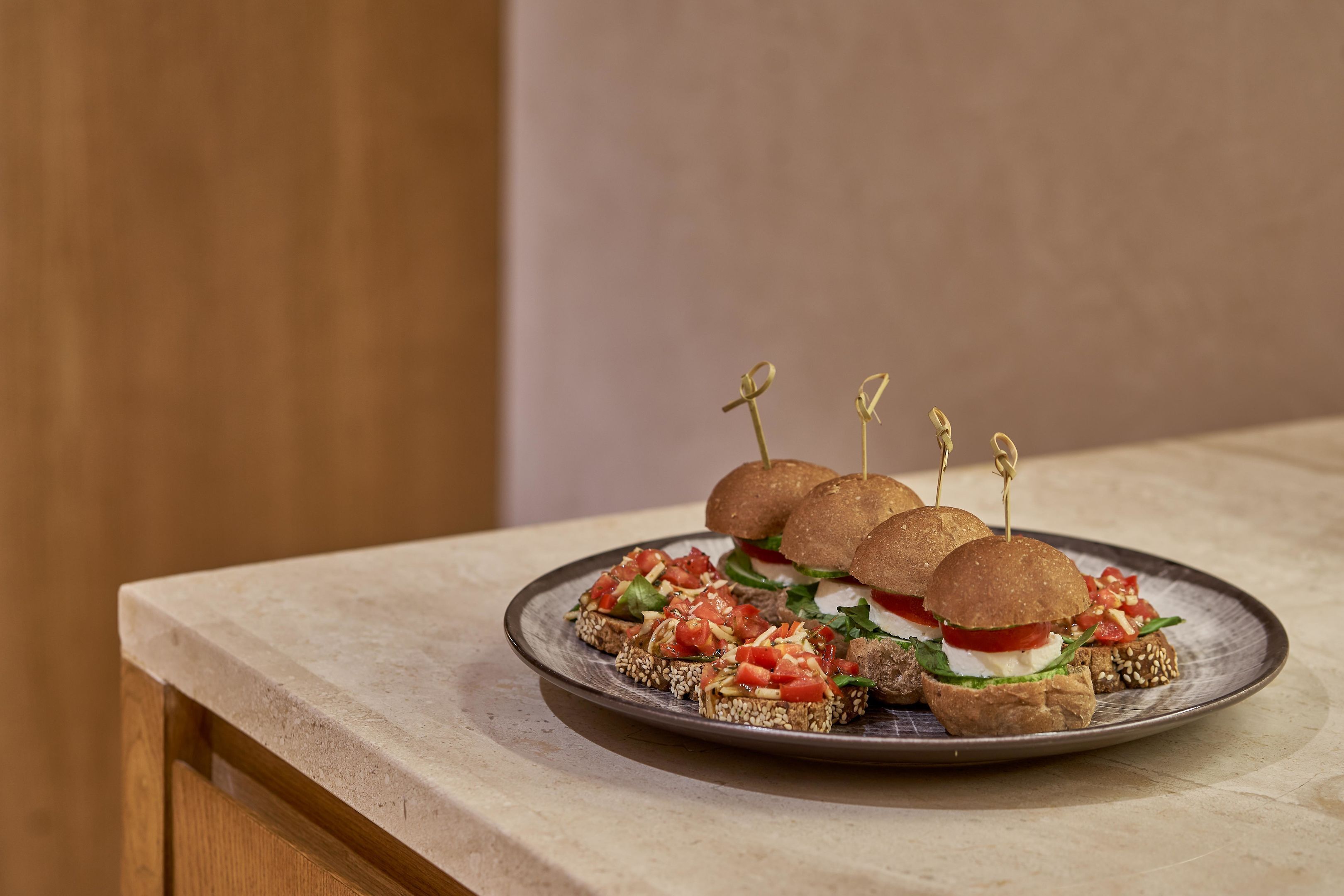 A plate of sandwiches with toothpicks on a ceramic plate.
