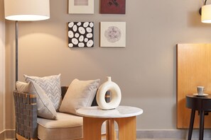 Een moderne woonkamer met een bank, een ronde houten tafel en een lamp.
