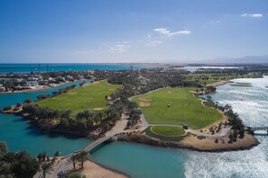 An aerial view of a coastal golf course with a bridge, water bodies, and surrounding greenery. - Steigenberger Golf Resort El Gouna (El Gouna)