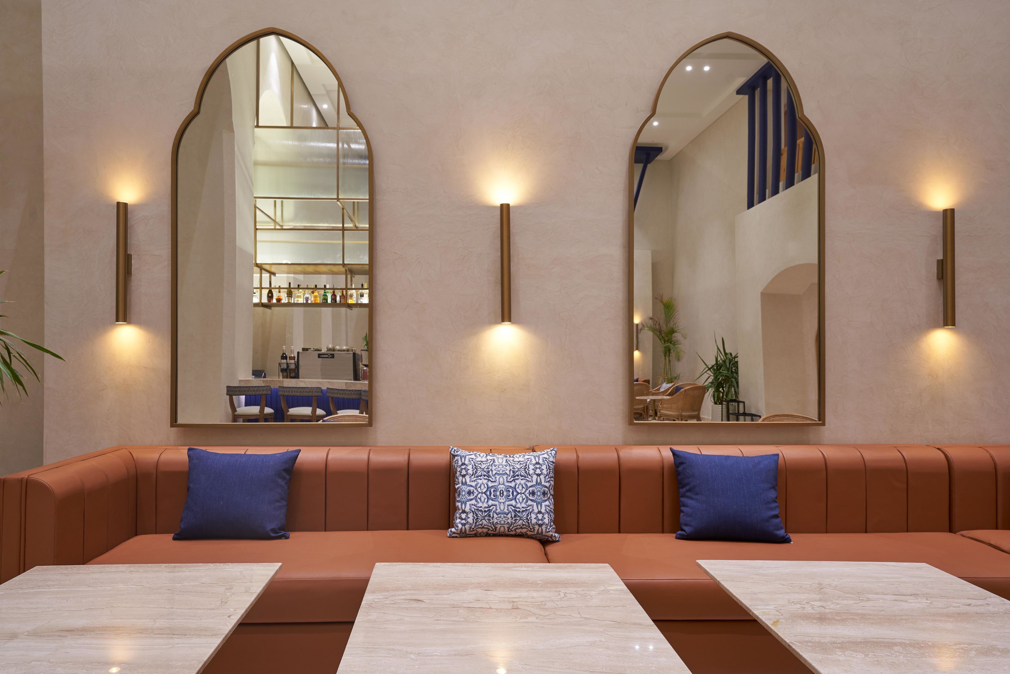 A modern interior with a brown leather sofa, two blue pillows, and a marble table.