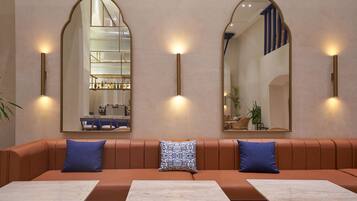 A modern interior with a brown leather sofa, two blue pillows, and a marble table.