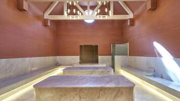 Un spa moderno con suelo de mármol, una zona de estar central y un espejo grande.