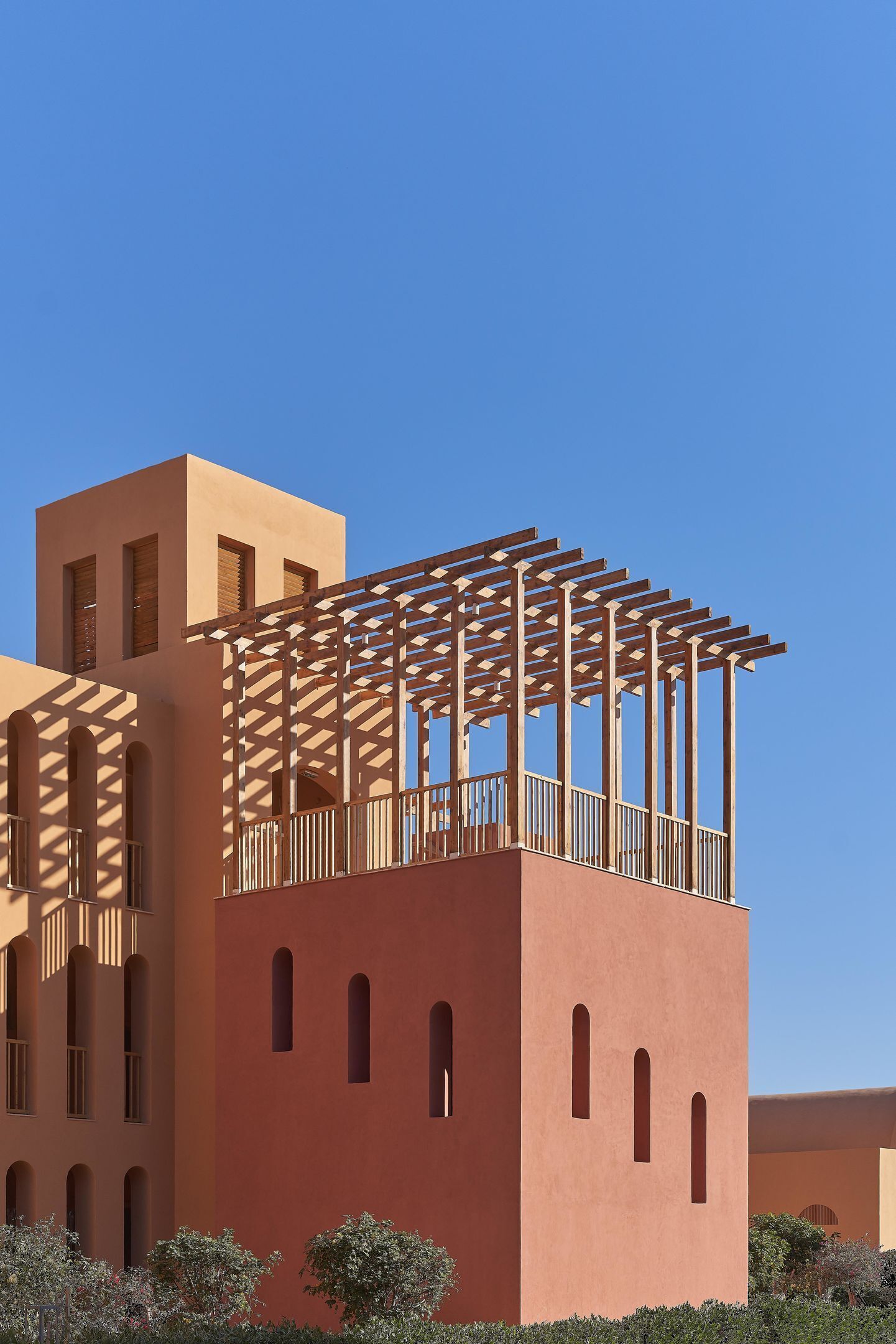 A building with a modern architectural style, featuring a prominent balcony with a wooden pergola.