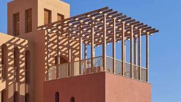 Um edifício com estilo arquitetônico moderno, apresentando uma varanda notável com pérgola de madeira.