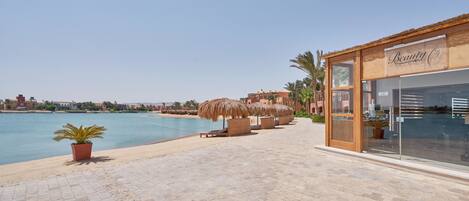 A beachfront hotel with a pool, lounge chairs, and umbrellas.