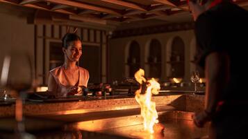 Zona de bar con chimenea, barra y una persona de pie.