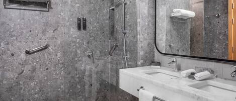 Une salle de bain moderne avec un mur en marbre, un grand miroir, un lavabo et un espace douche.