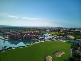 Un gran complejo turístico con un edificio central, un río y un campo de golf.
