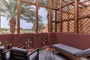 Un balcon doté d’une structure en treillis de bois, d’un banc rembourré et d’une petite table sur laquelle se trouvent un vase et deux verres.