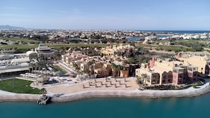 An aerial view of a resort with a pool, palm trees, and a beach.